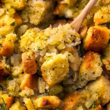 overhead close up photo of wooden spoon scooping stuffing from casserole