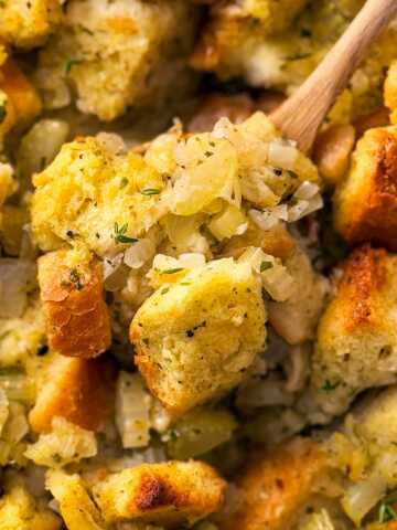 overhead close up photo of wooden spoon scooping stuffing from casserole