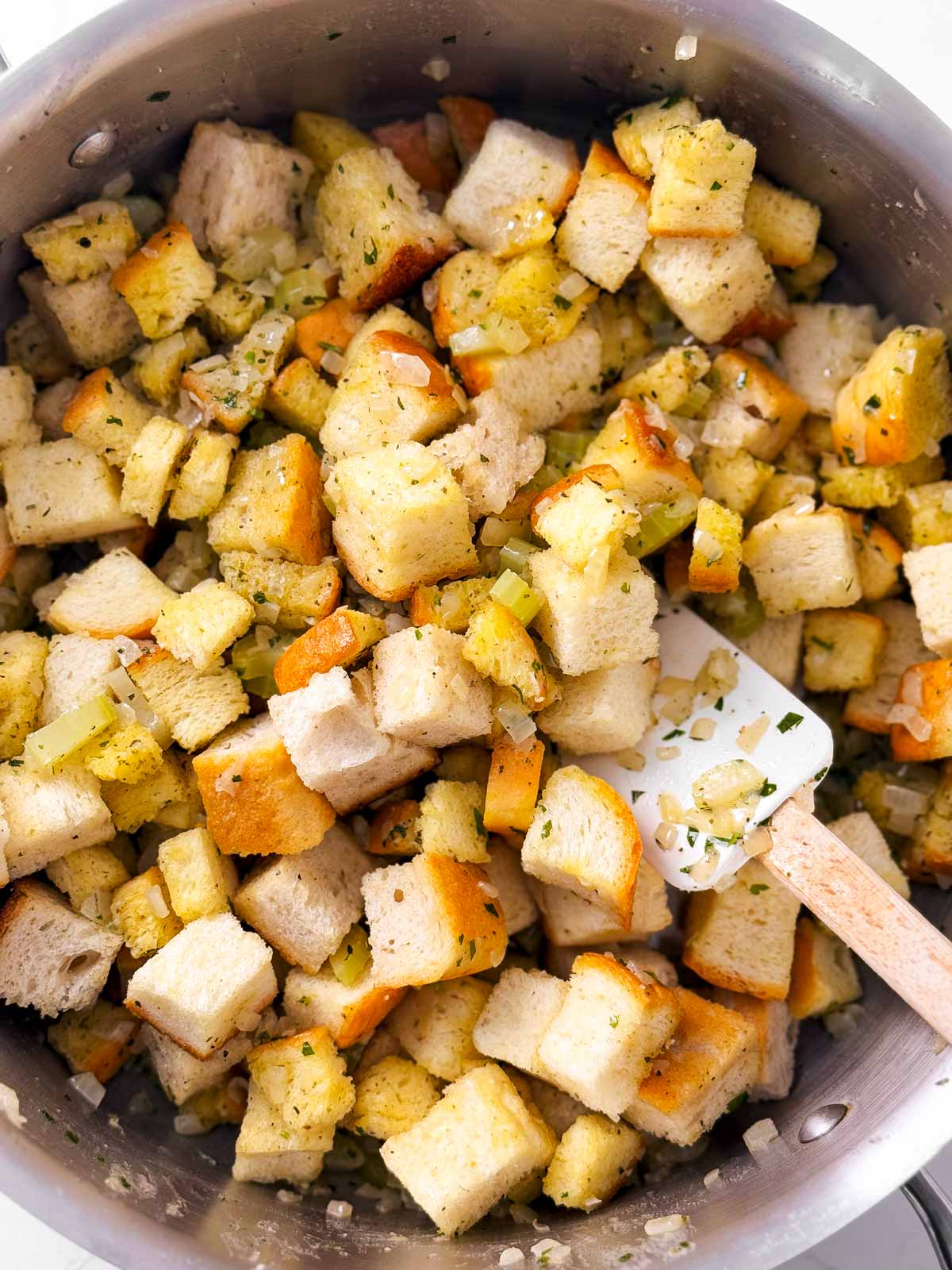 overhead view of bread cubes combined with cooked celery and onion