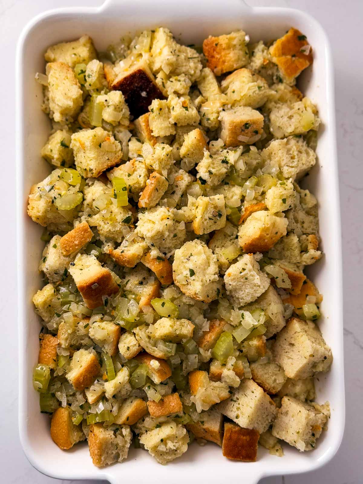 overhead view of uncooked stuffing in white casserole dish