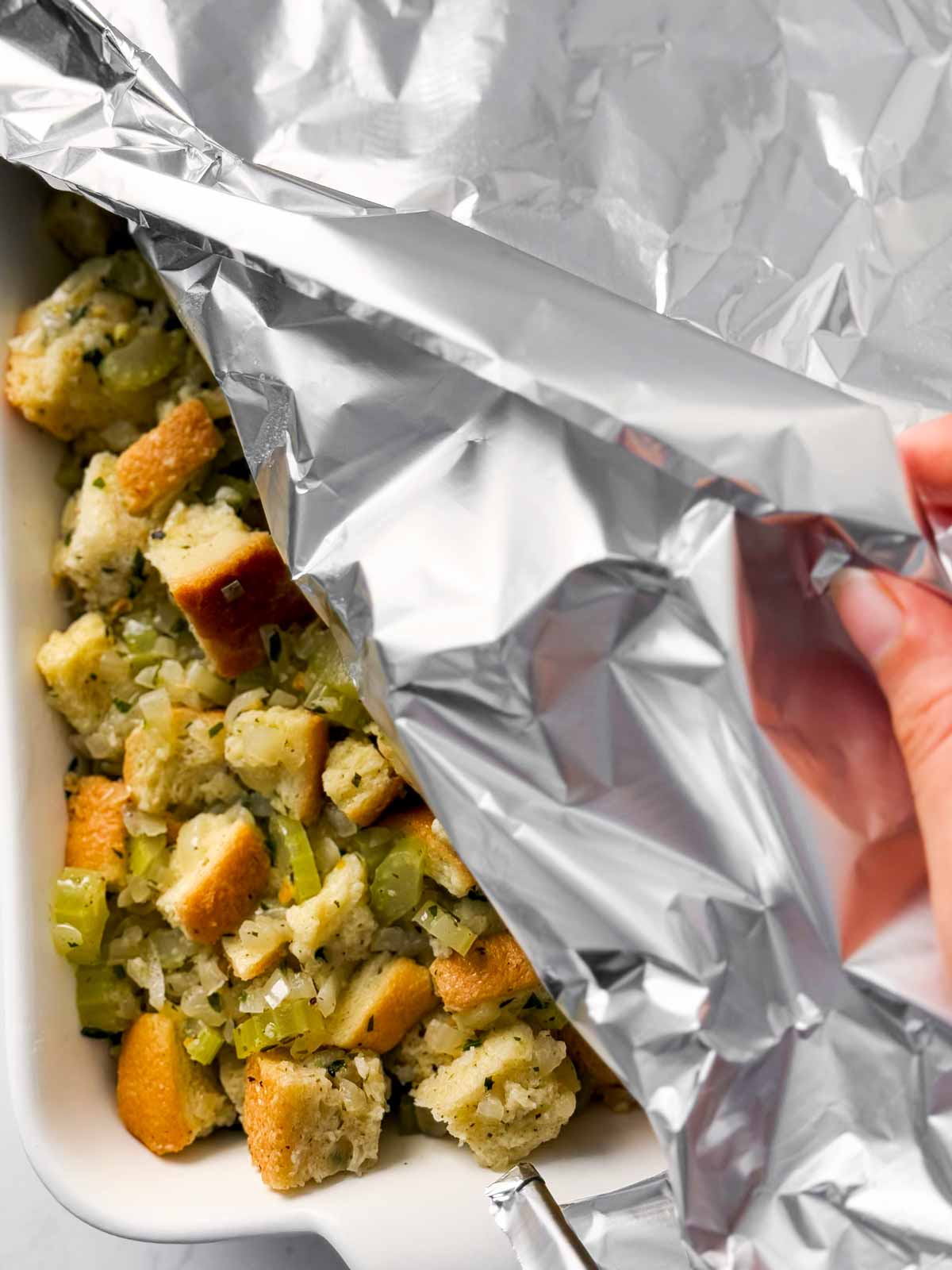 overhead view of female hand covering stuffing with foil