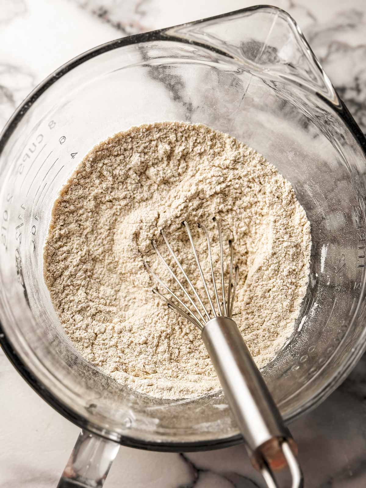 overhead view of dry ingredients in glass bowl with whisk