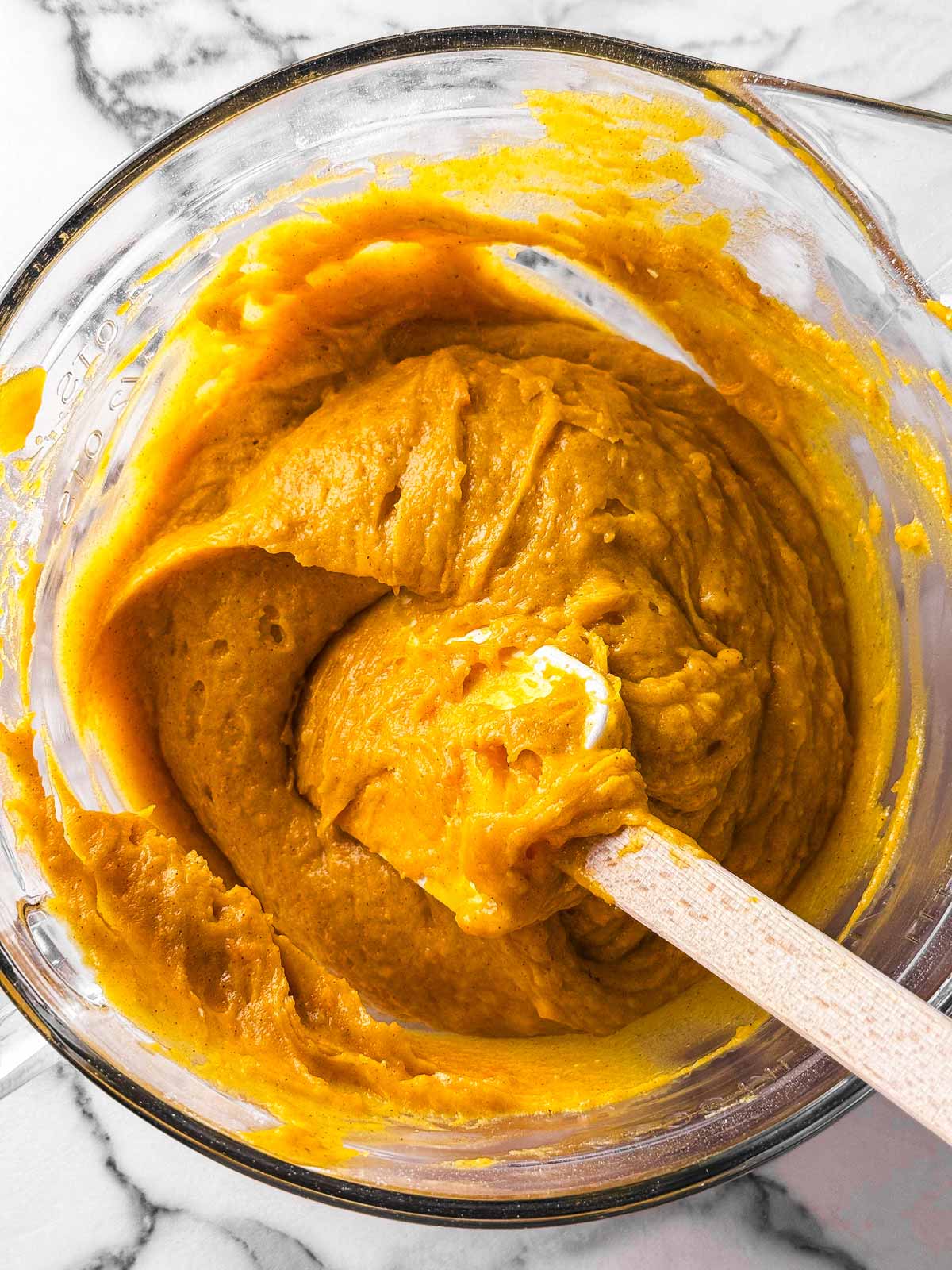 overhead view of pumpkin bread batter in glass bowl with rubber spatula