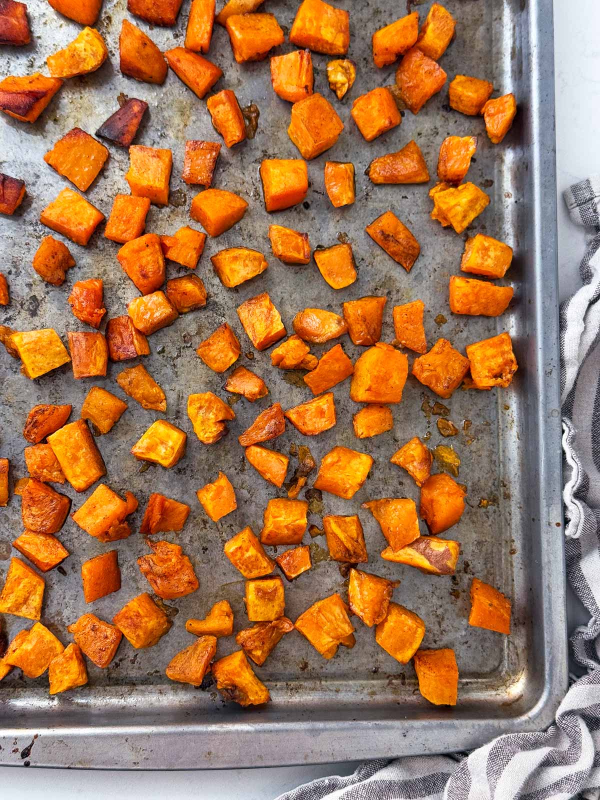 overhead close up view of roasted sweet potato cubes on sheet pan