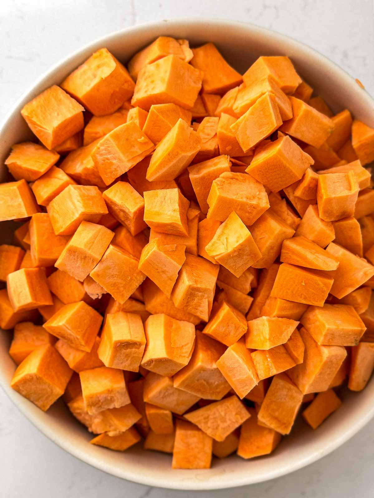 overhead view of diced sweet potatoes in white bowl