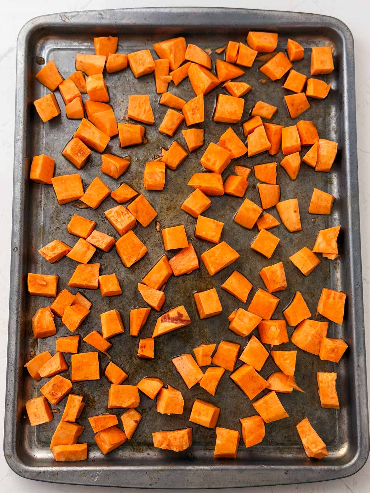 overhead view of sweet seasoned sweet potatoes on sheet pan