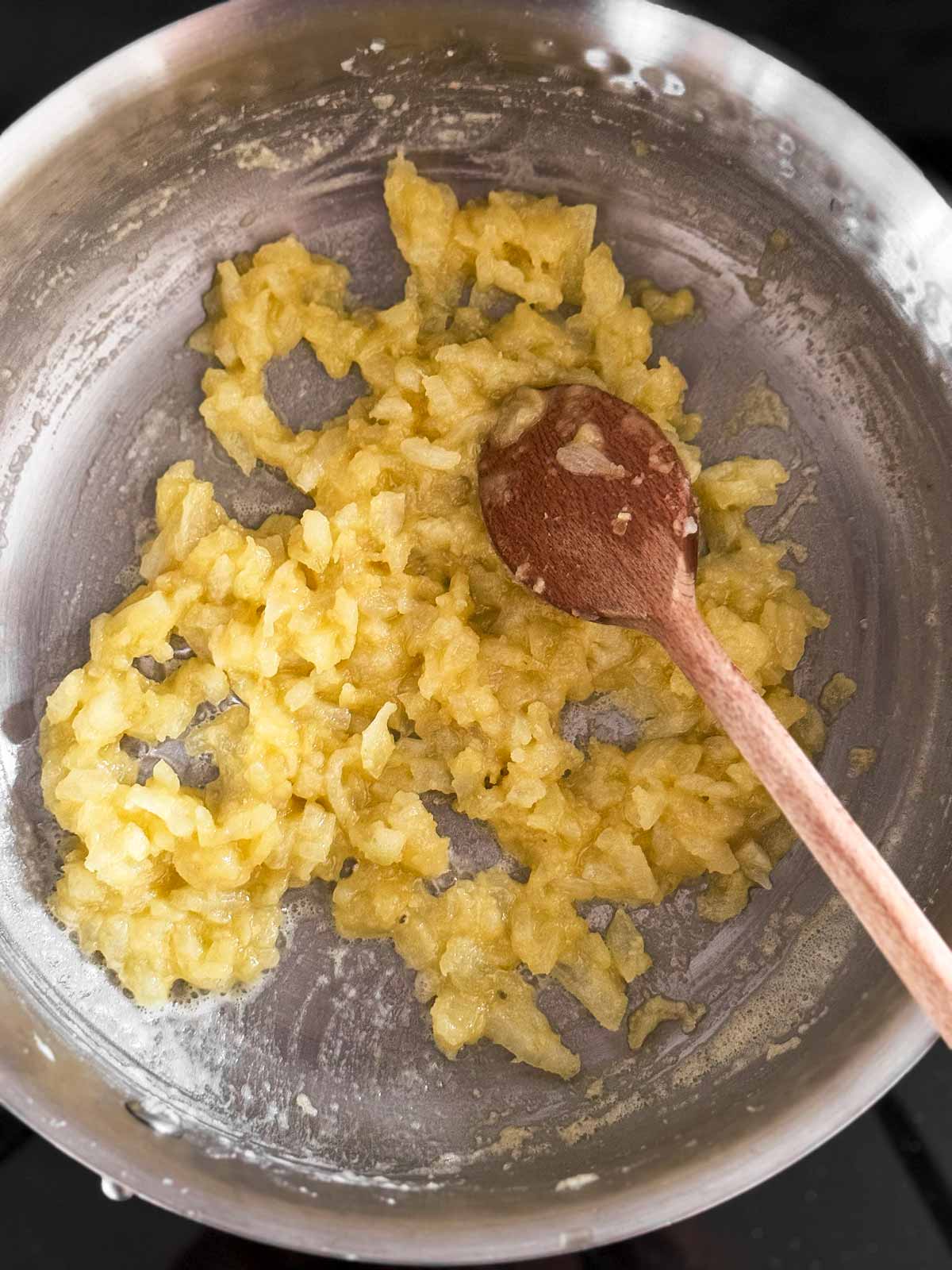 overhead view of roux with onion in saucepan with wooden spoon