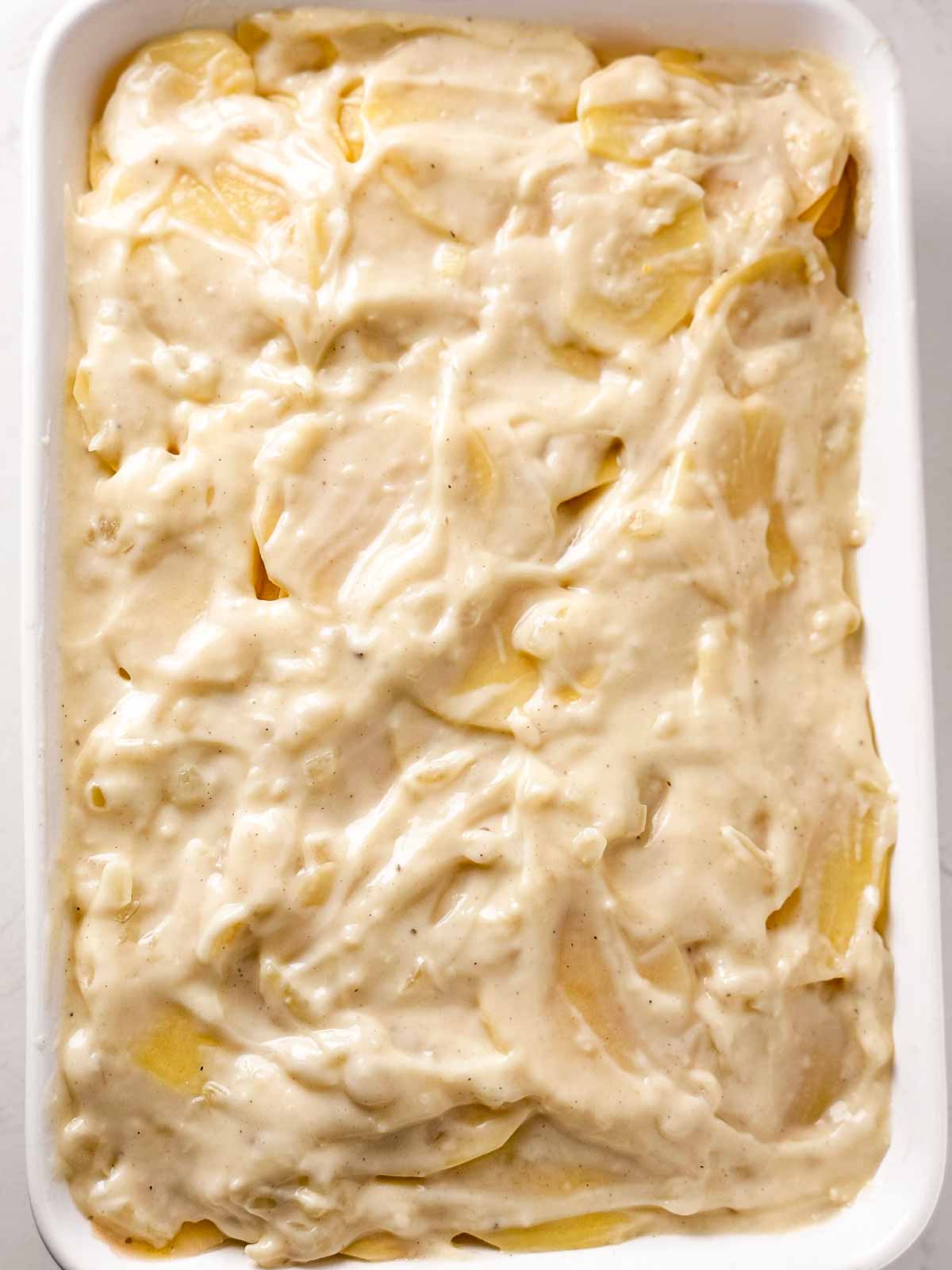 overhead view of unbaked scalloped potatoes in white casserole dish