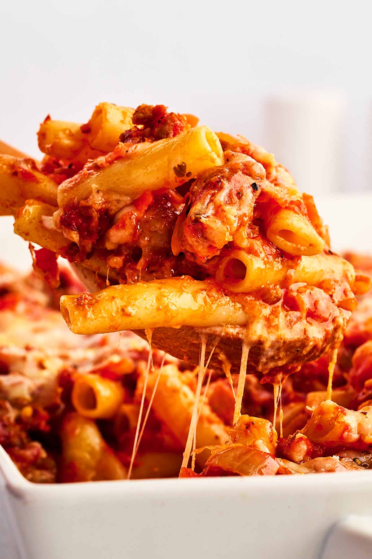 frontal view of baked ziti being scooped from a casserole dish