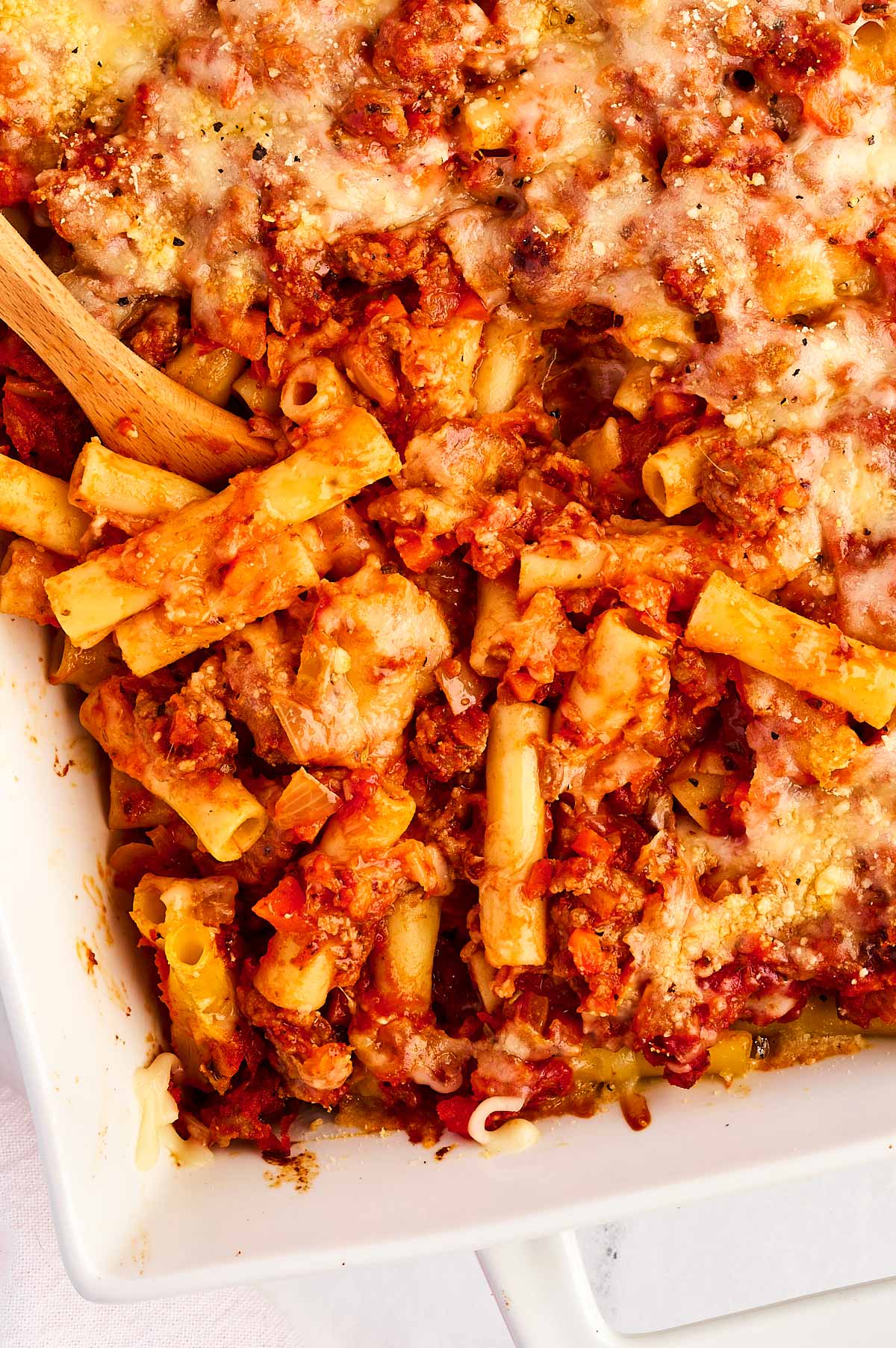 overhead view of bake ziti in white casserole dish with spoon stuck in