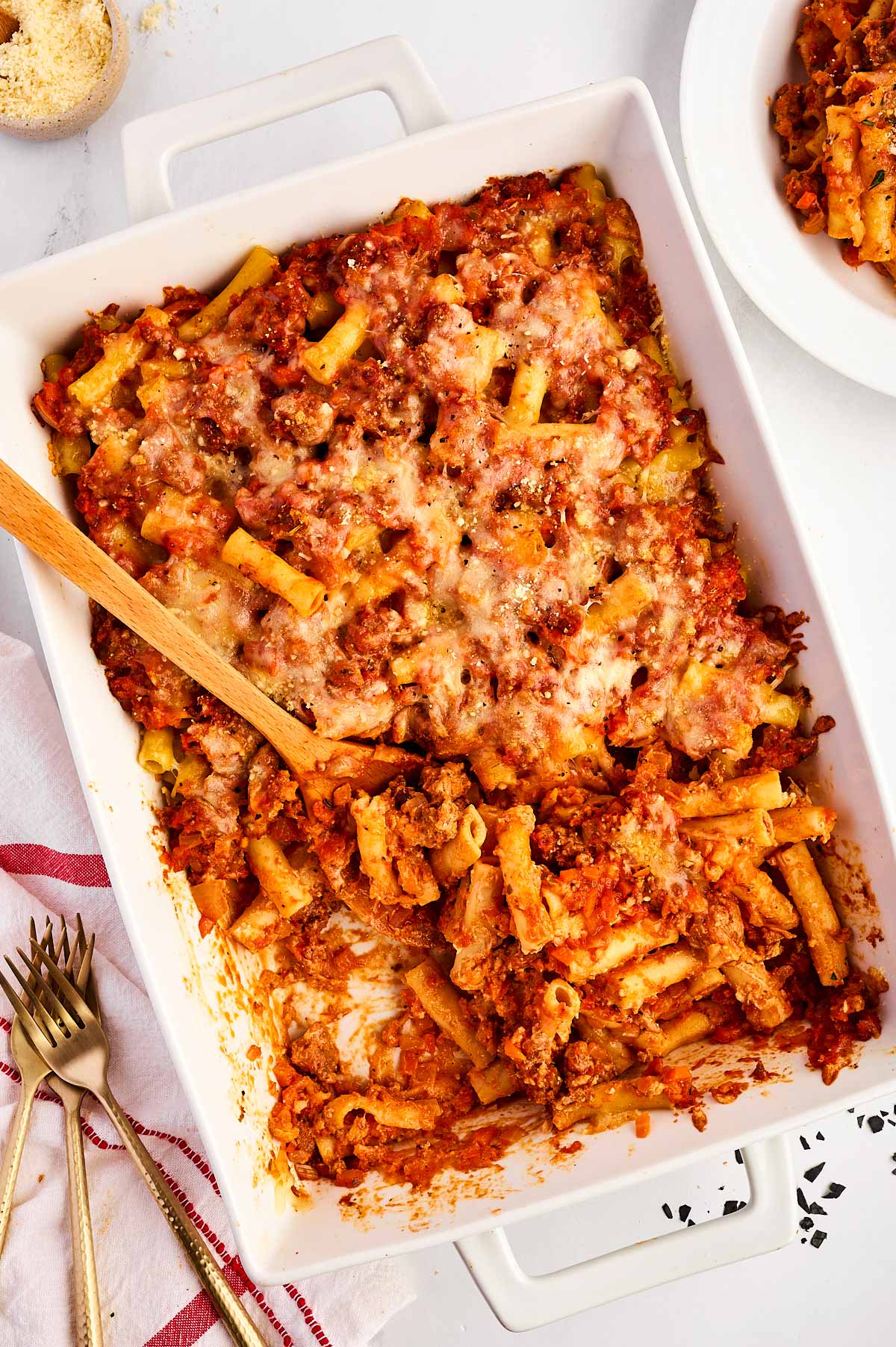 overhead view of baked ziti in casserole dish with wooden spoon stuck in