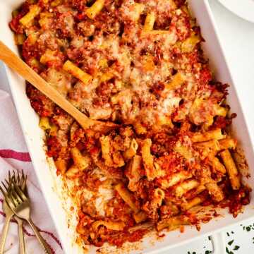 overhead view of baked ziti in casserole dish with wooden spoon stuck in