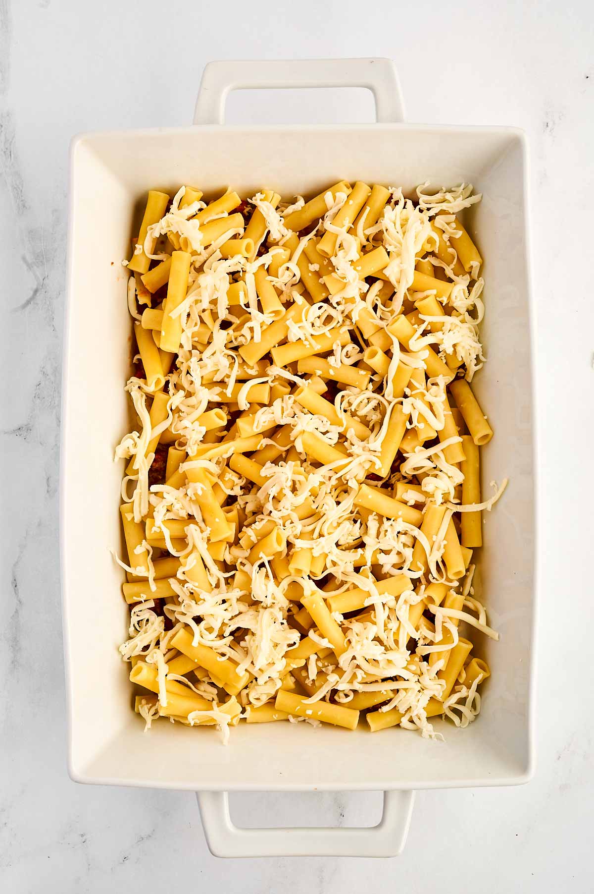 overhead view of cooked pasta with cheese in white casserole dish