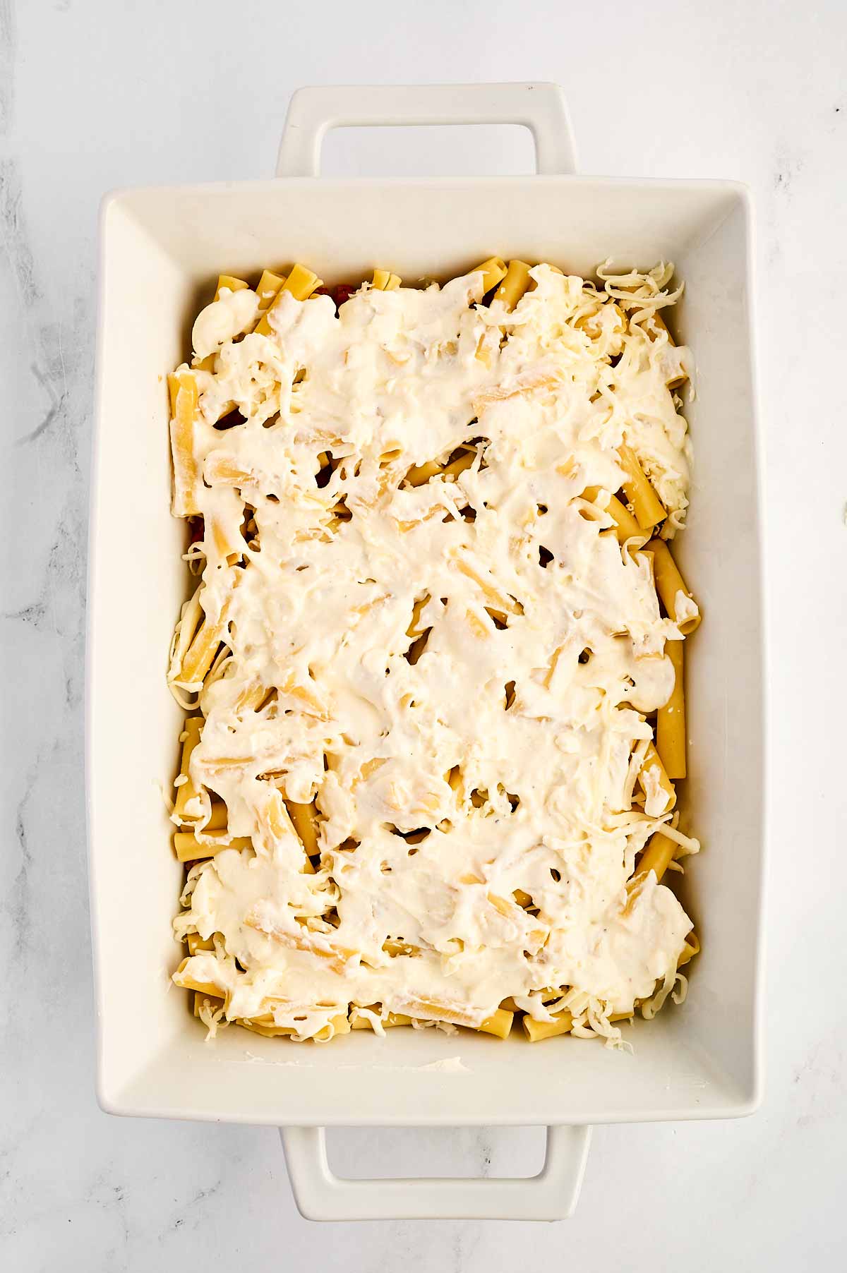 overhead view of cooked pasta with cheese sauce in white casserole dish