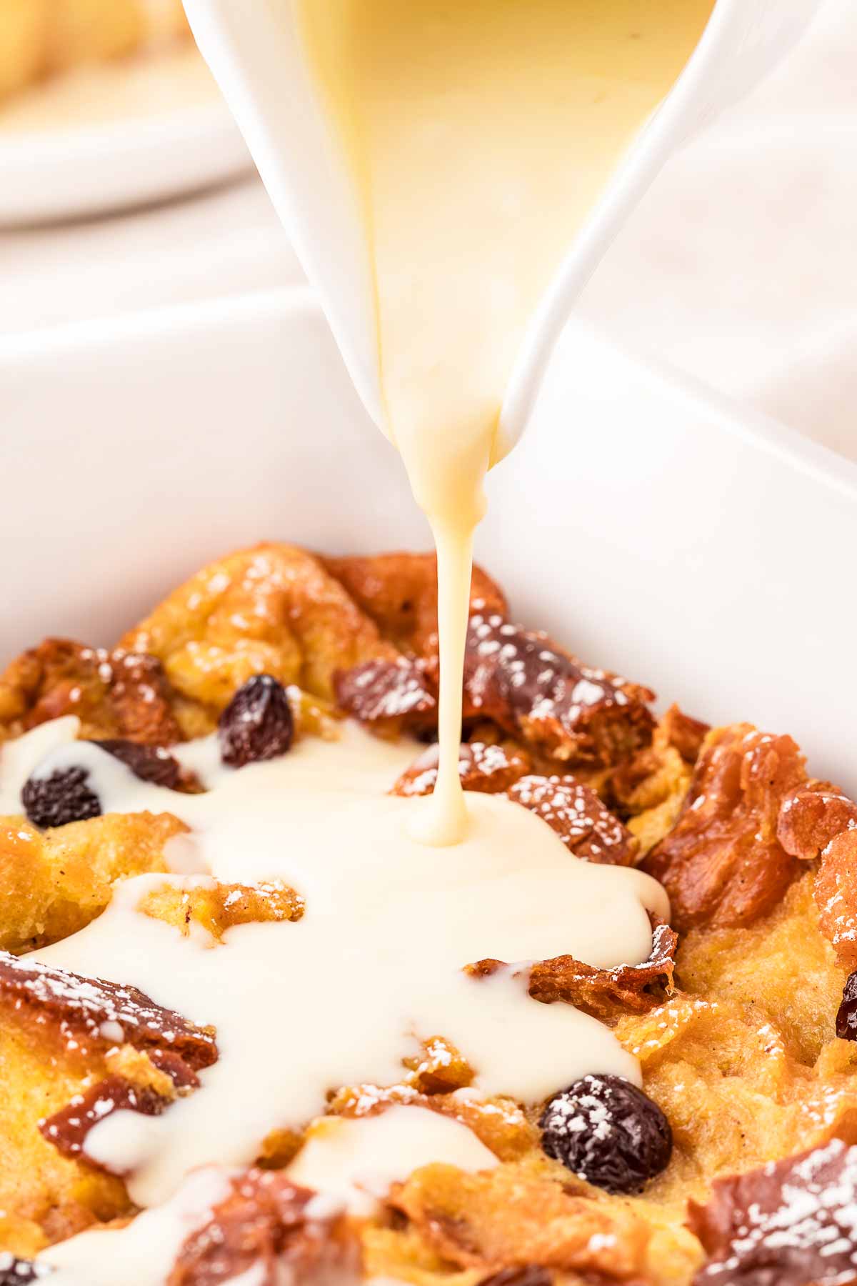 frontal view of custard drizzling over bread pudding in casserole dish