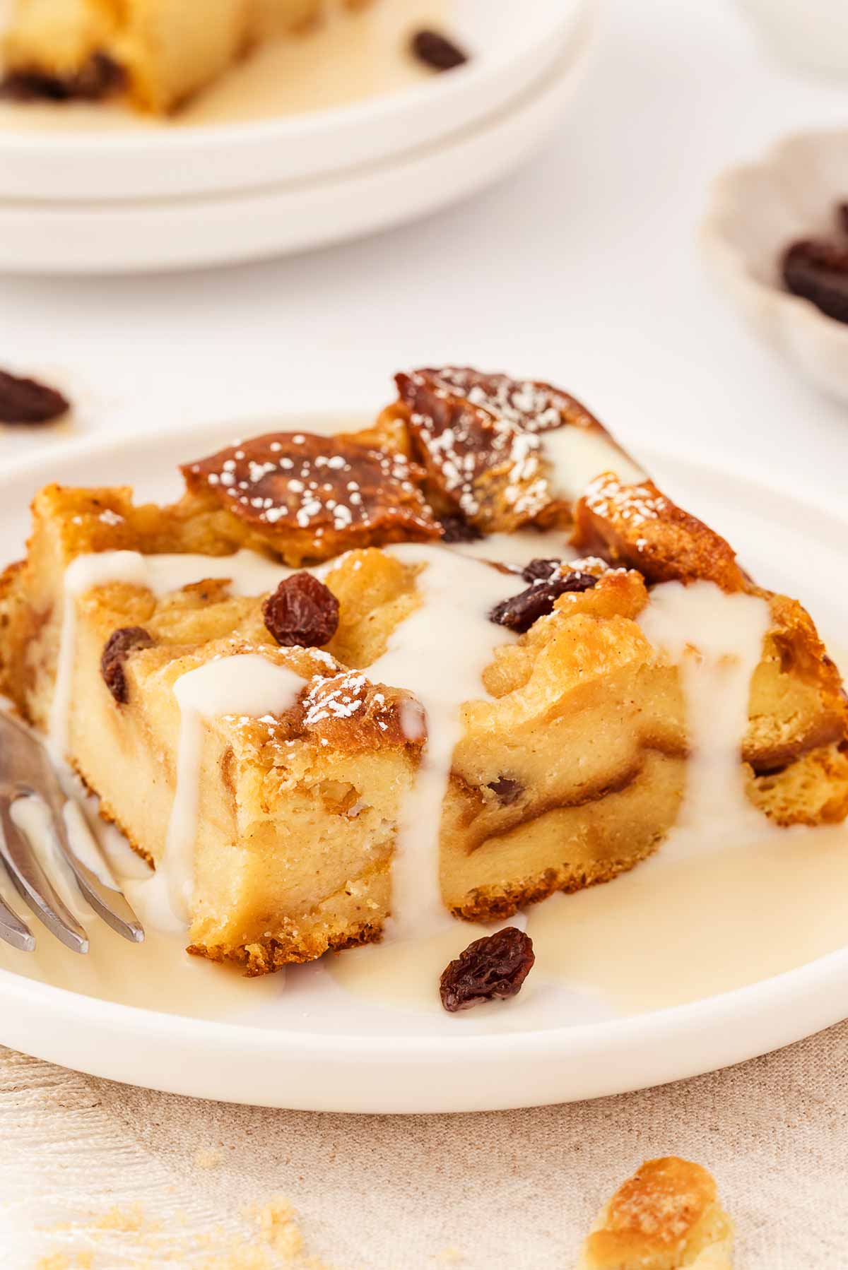 frontal view of custard dripping over slice of bread pudding on white plate