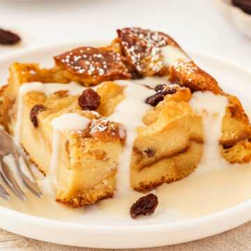 frontal view of custard dripping over slice of bread pudding on white plate