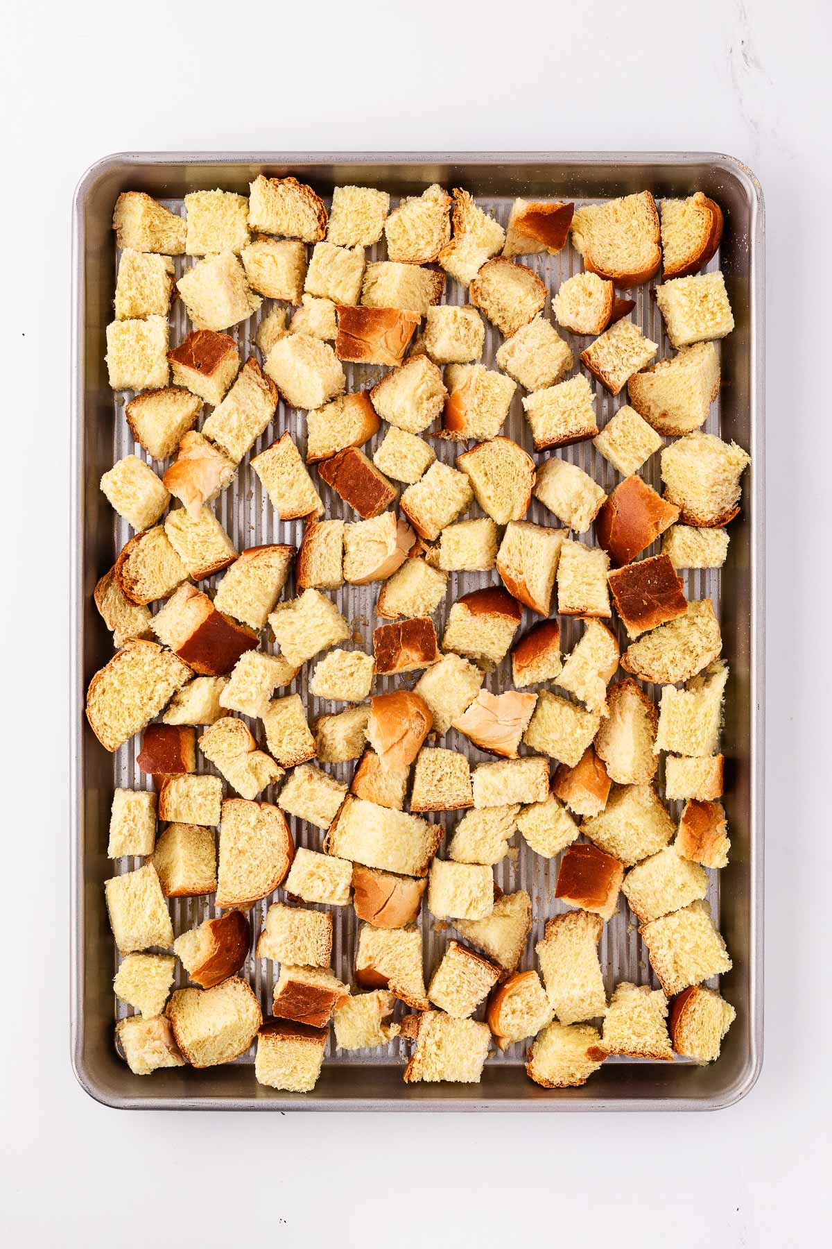 overhead view of cubed bread on baking sheet