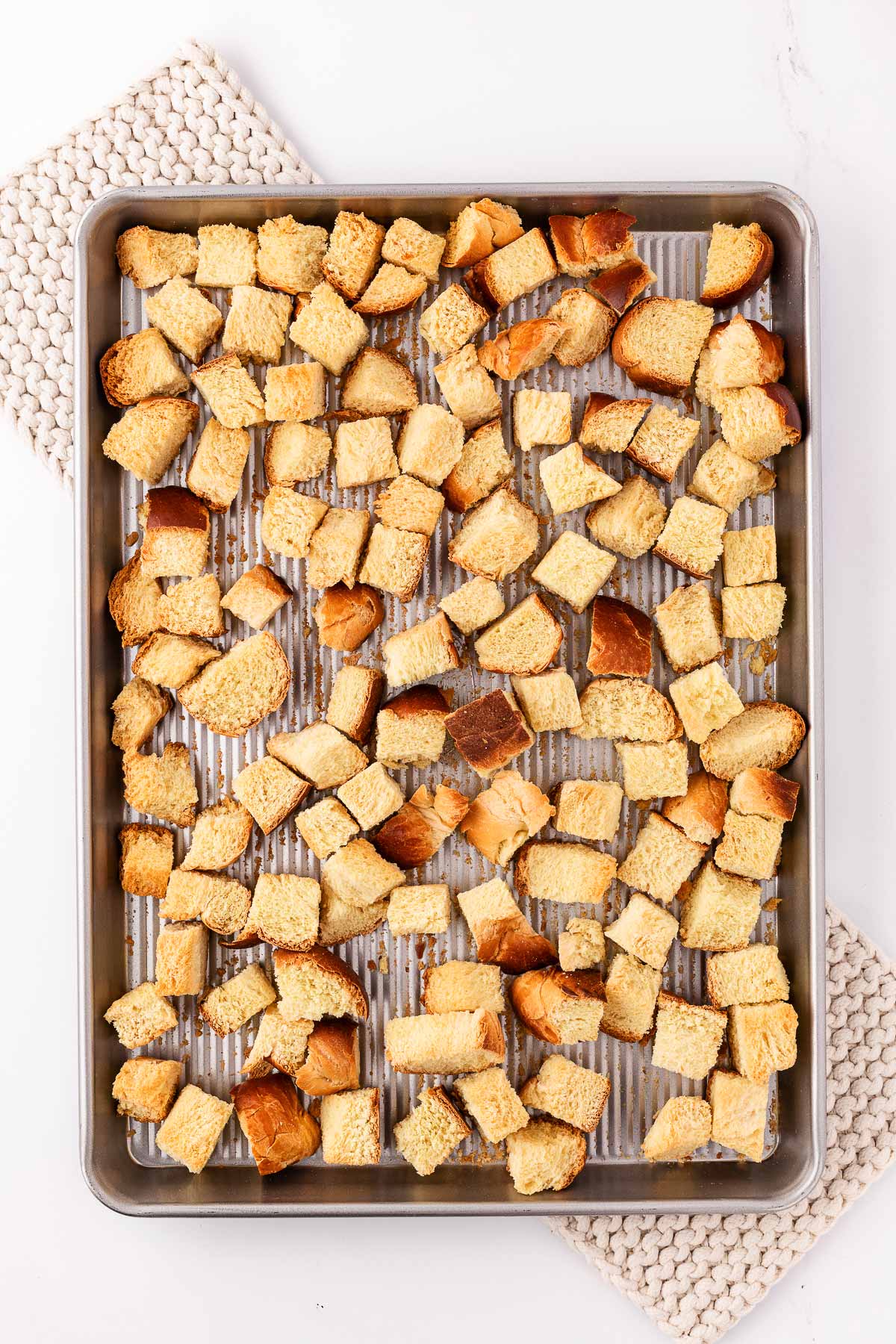 overhead view of dried bread cubes on baking sheet