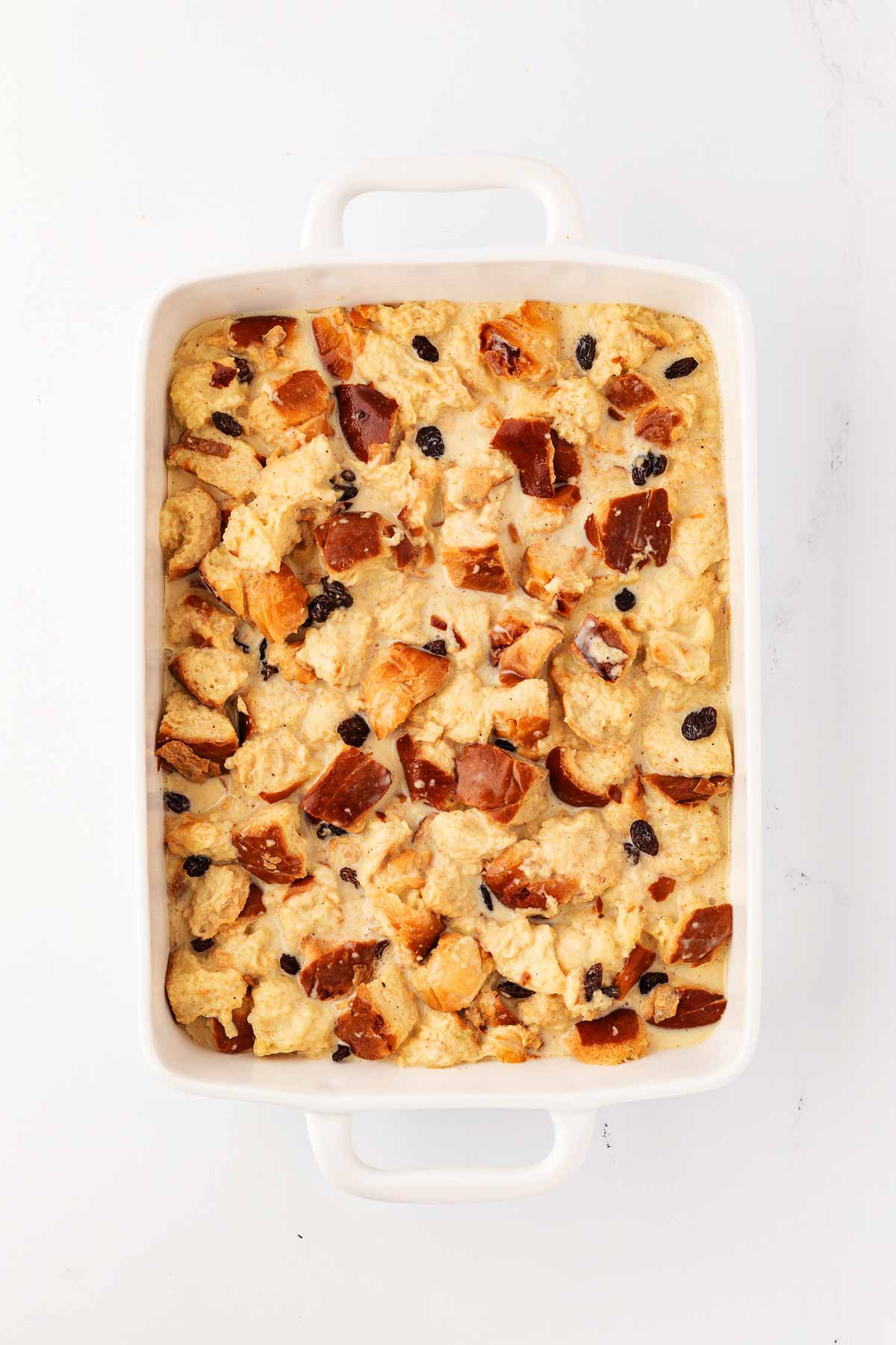 overhead view of unbaked bread pudding in white casserole dish