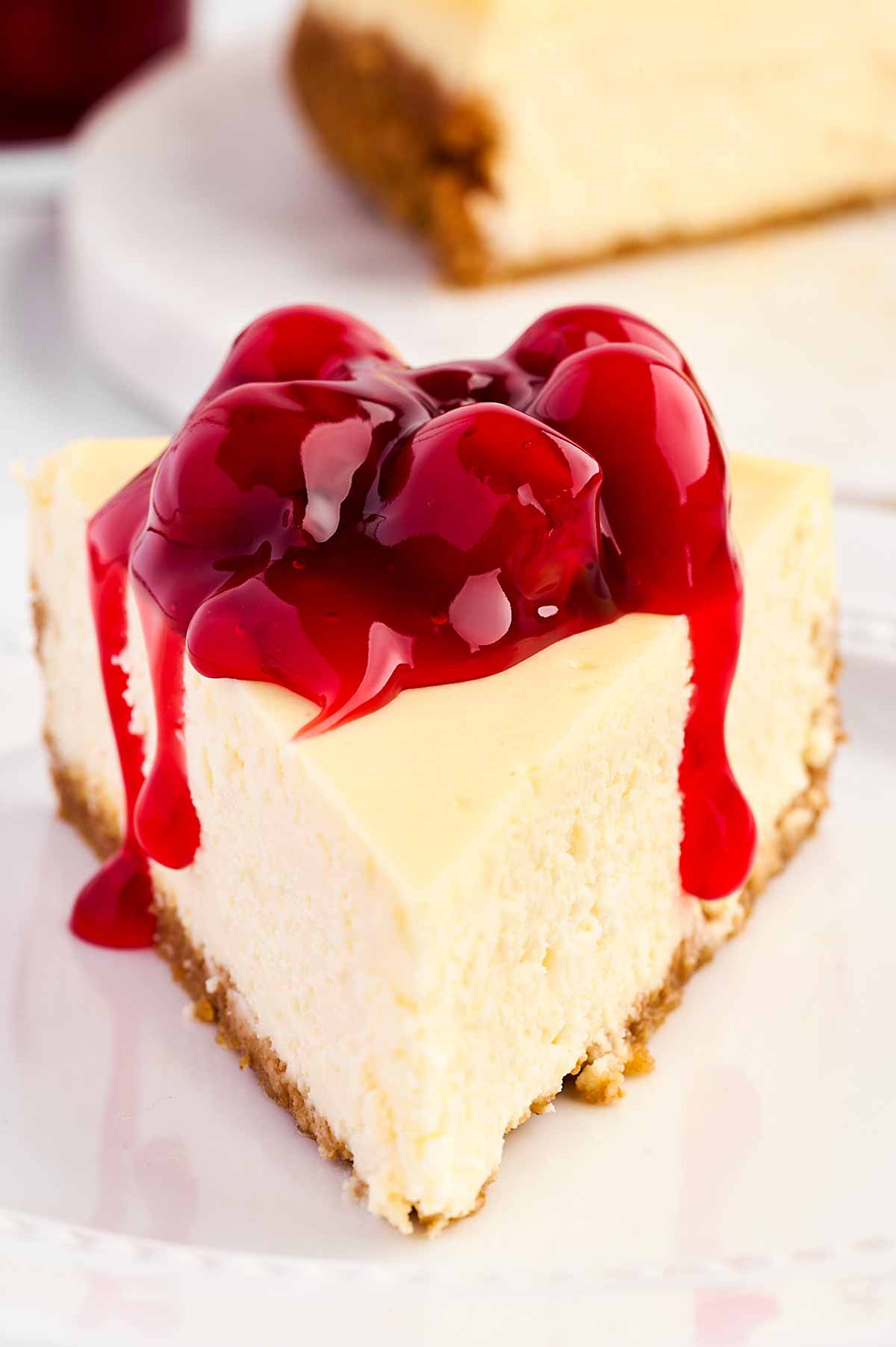 frontal view of cheesecake slice topped with cherry pie filling