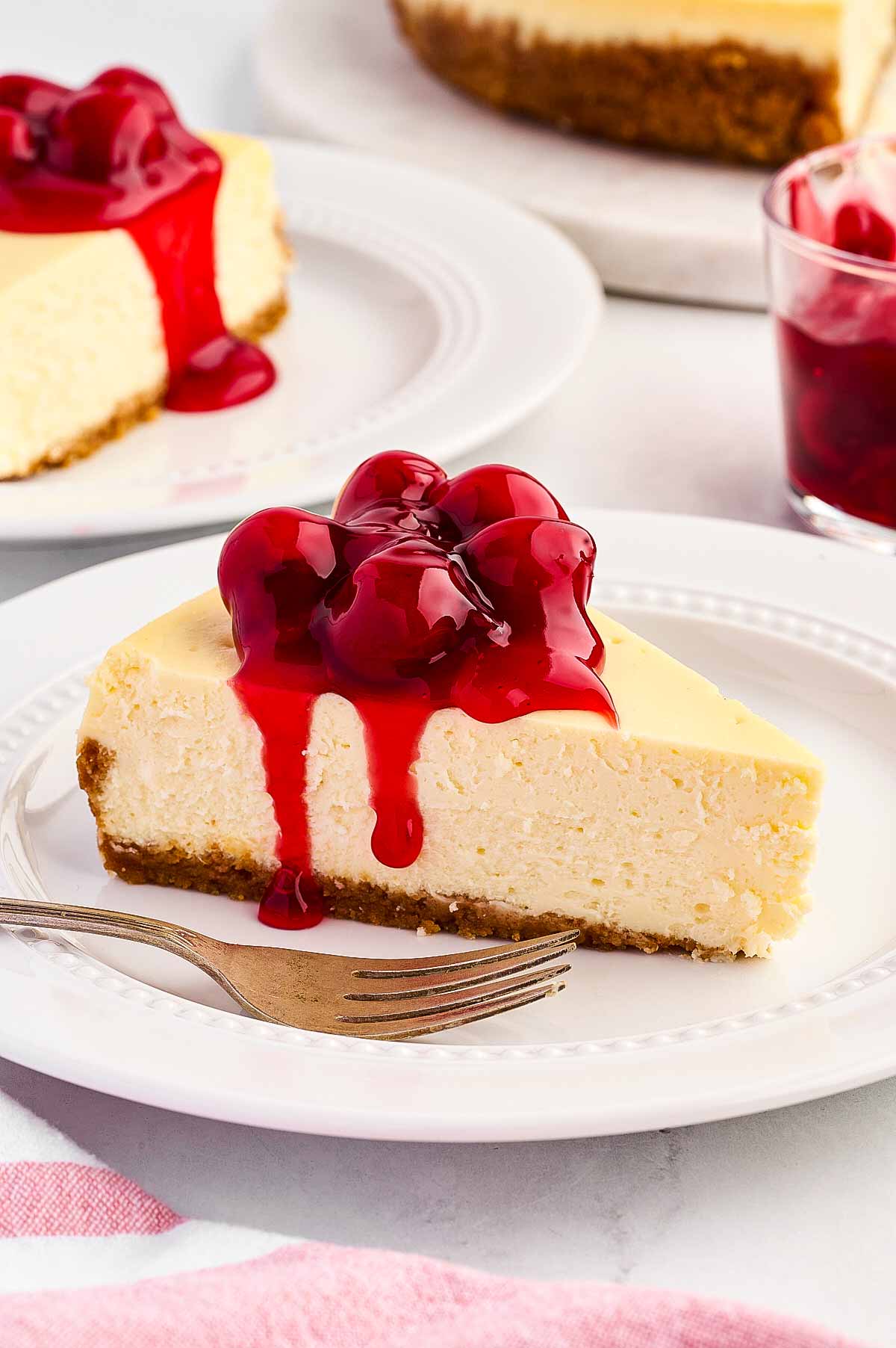 frontal view of cheesecake with cherry filling on white plate