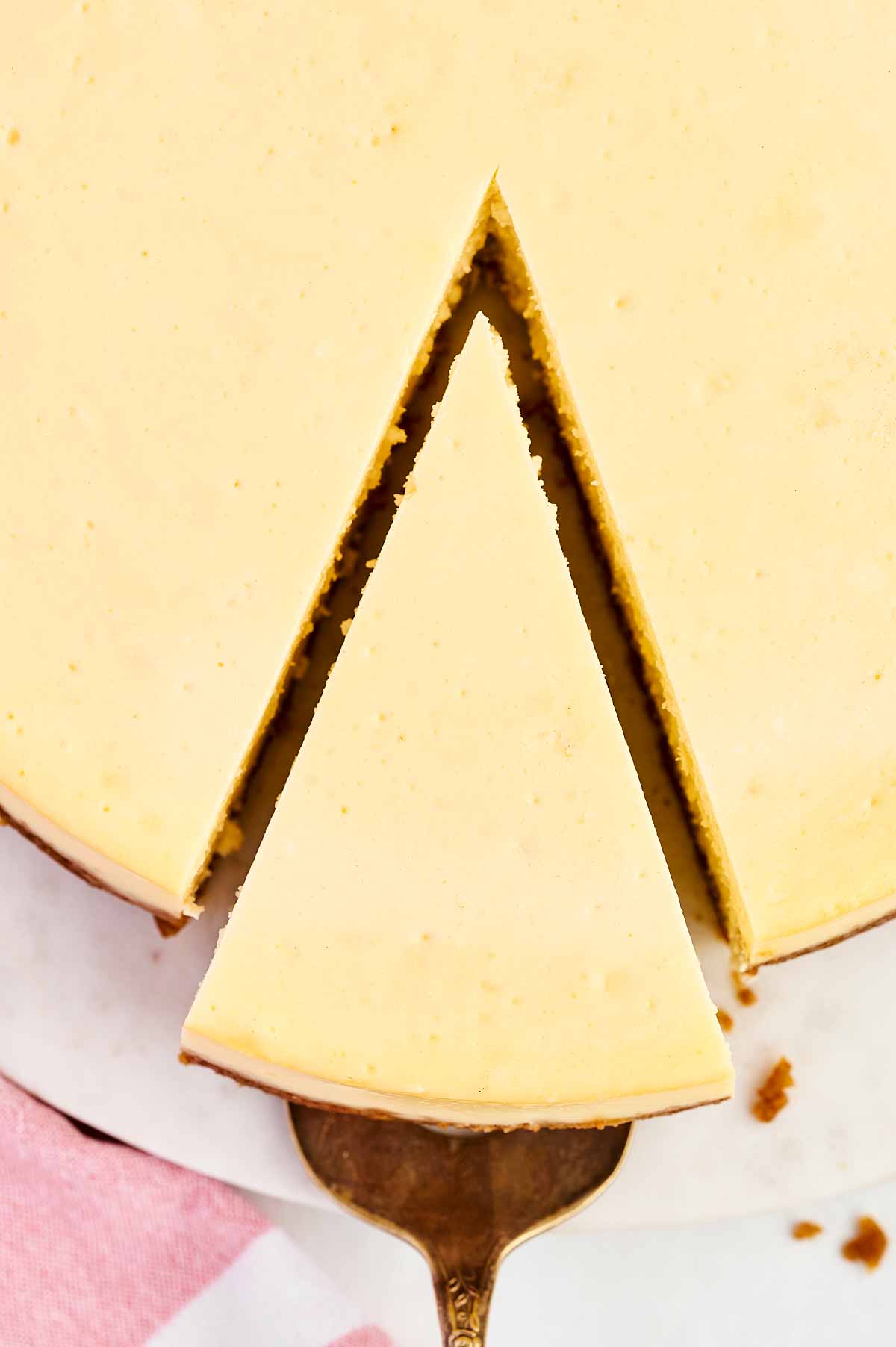 overhead close up view of cheesecake slice being removed from cheesecake