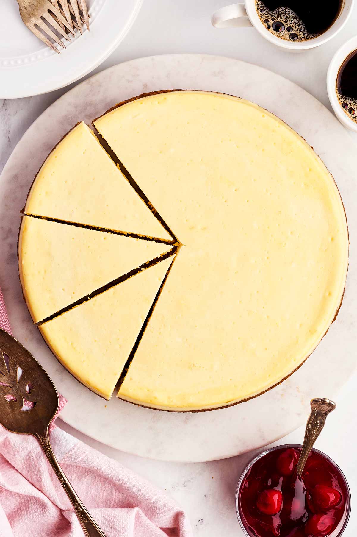 overhead view of cheesecake on marble platter with a few slices cut