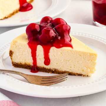 frontal view of cheesecake with cherry filling on white plate