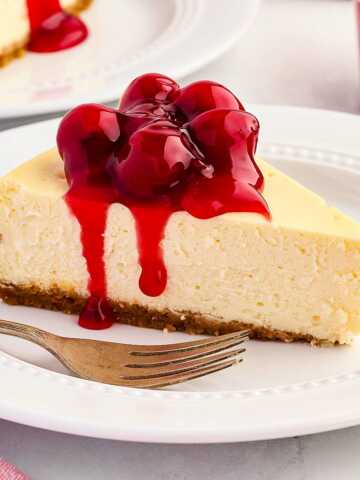 frontal view of cheesecake with cherry filling on white plate