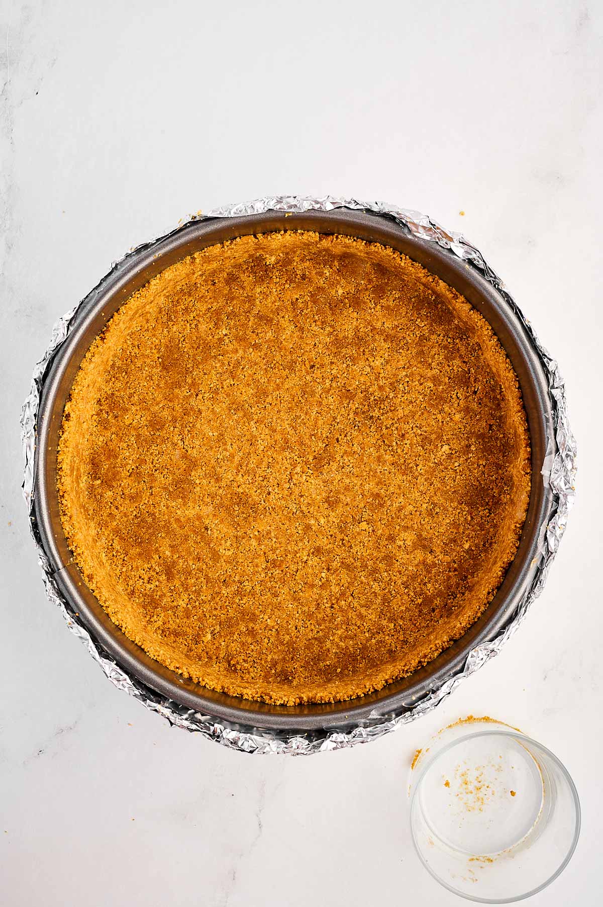 overhead view of graham cracker crust in springform pan