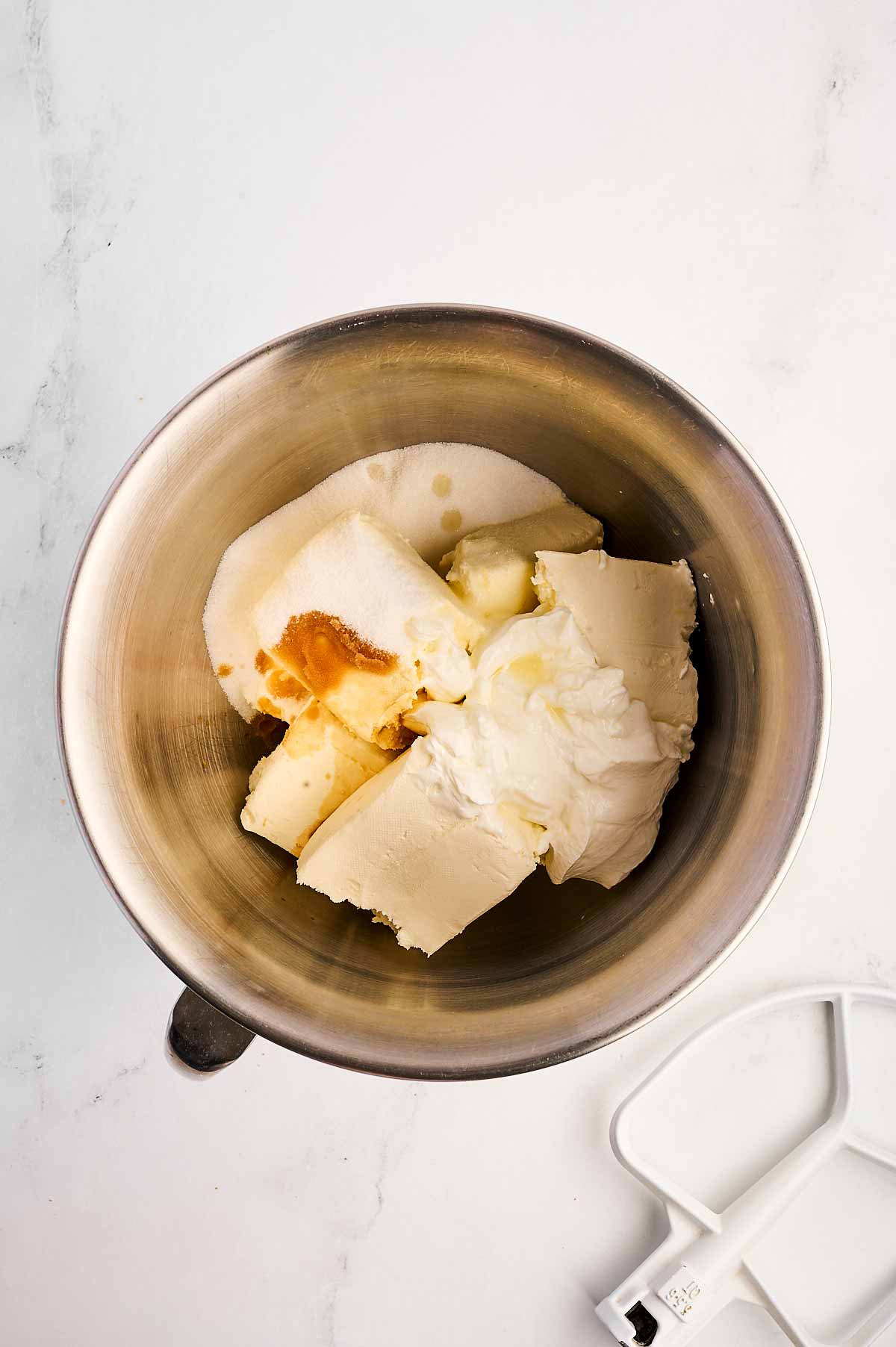 overhead view of cream cheese and sugar in bowl of a stand mixer