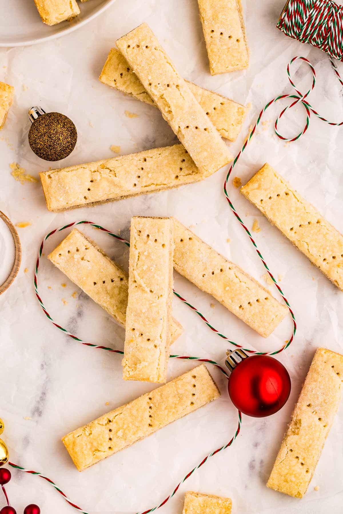 overhead view of shortbread cookie fingers with christmas decor on marble board