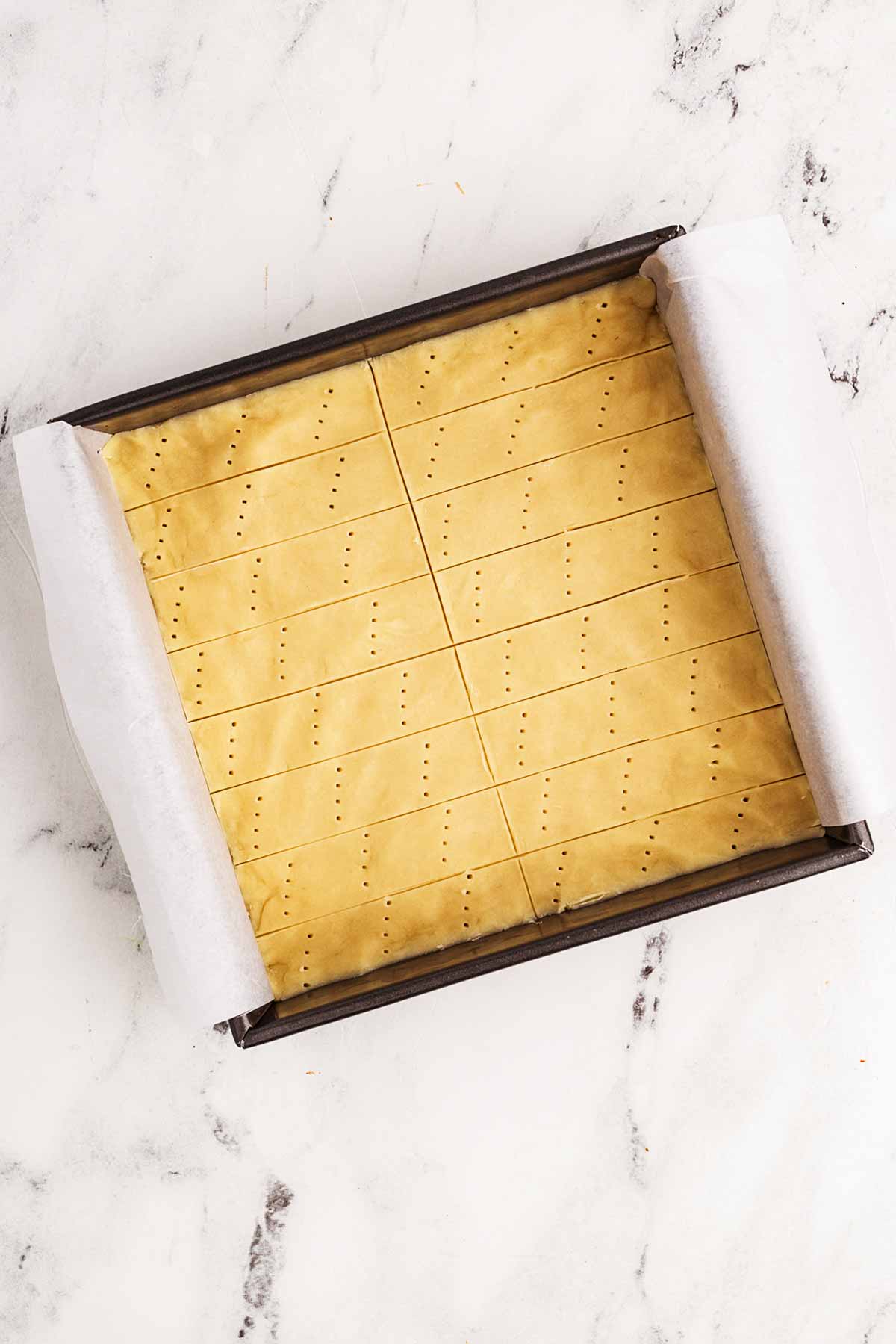 overhead view of unbaked shortbread cookies in square baking pan