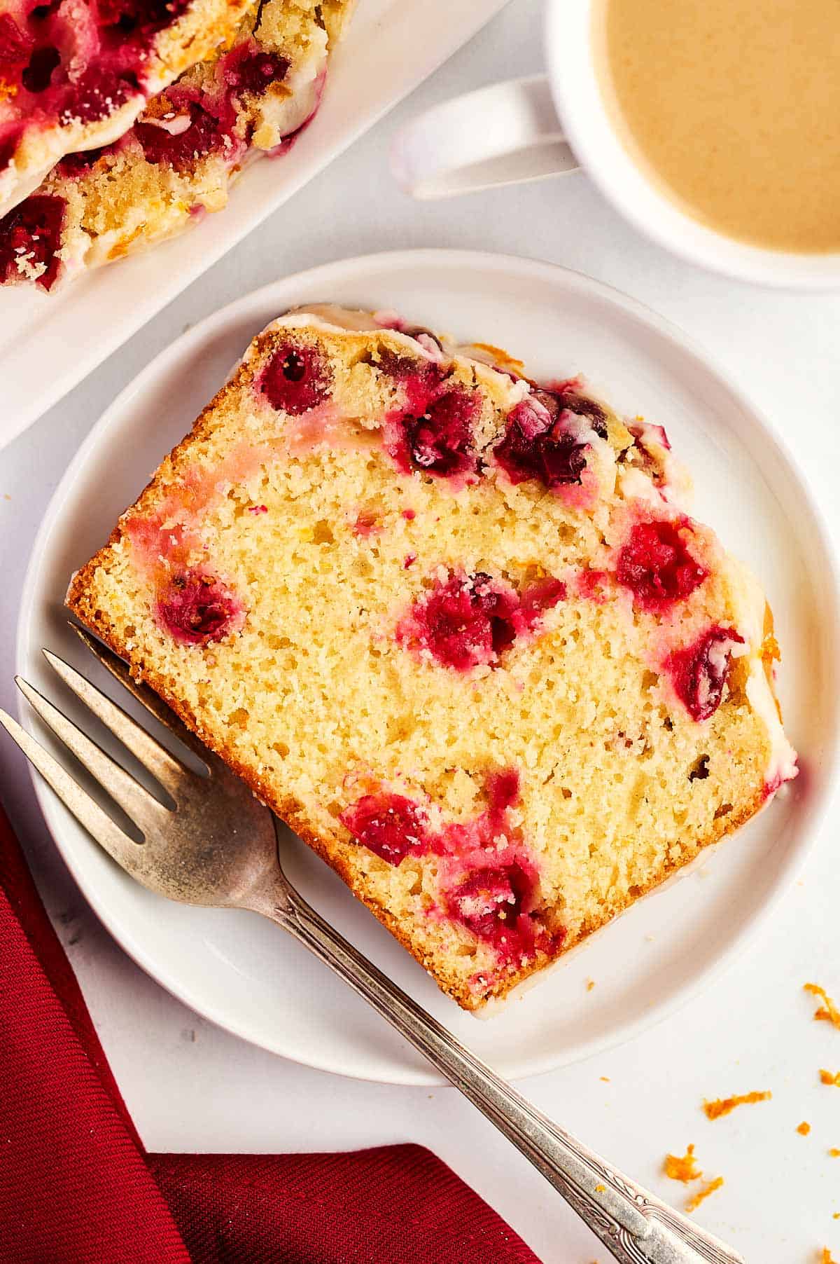 overhead view of cranberry orange bread slice on white plate with fork