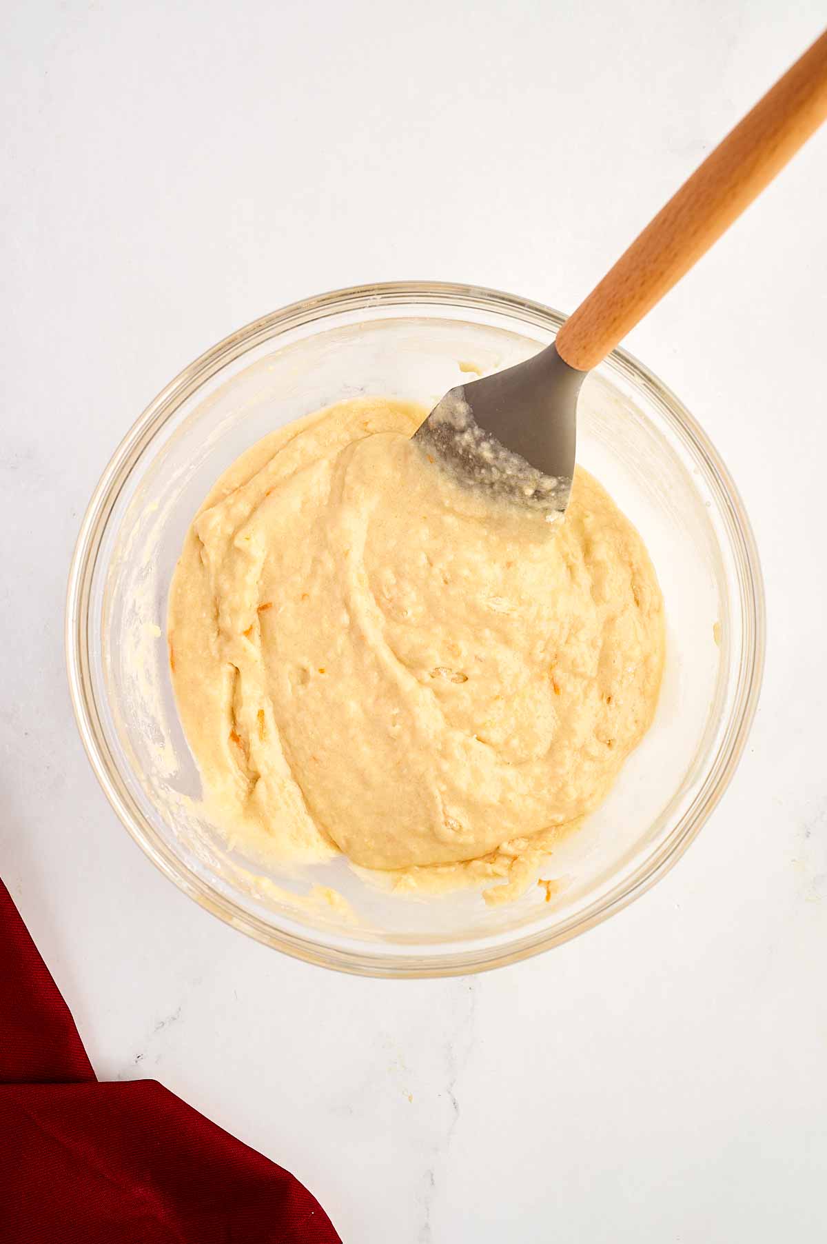 overhead view of cake batter in glass bowl with rubber spatula