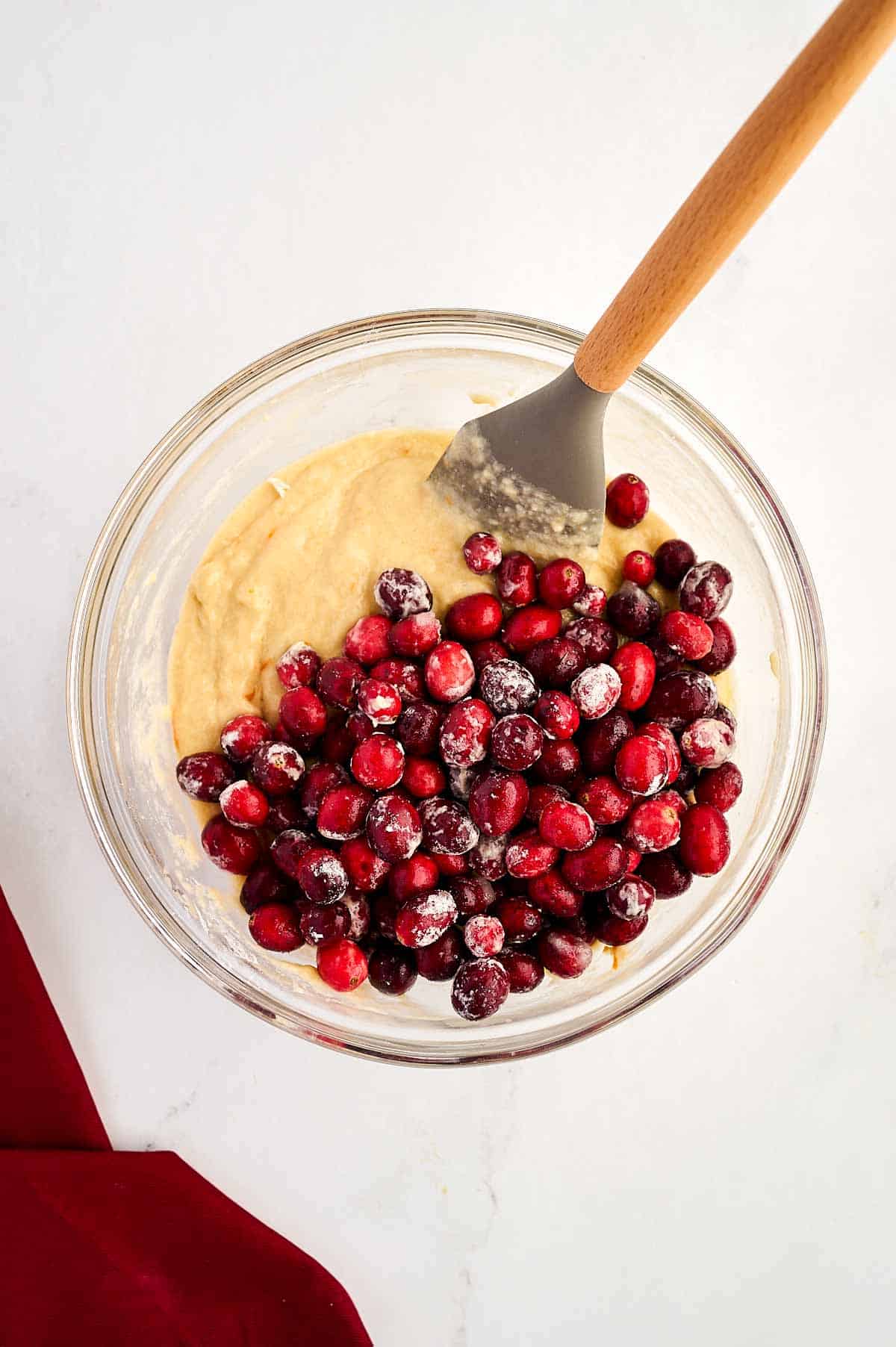 overhead view of cranberries on top of cake batter in glass bowl