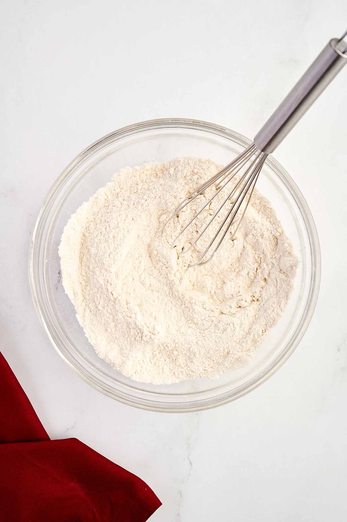 overhead view of mixed dry cake ingredients in a glass bowl with a whisk