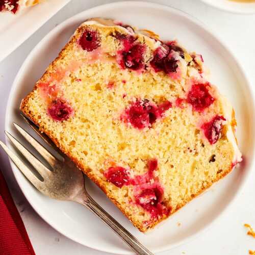 overhead view of cranberry orange bread slice on white plate with fork