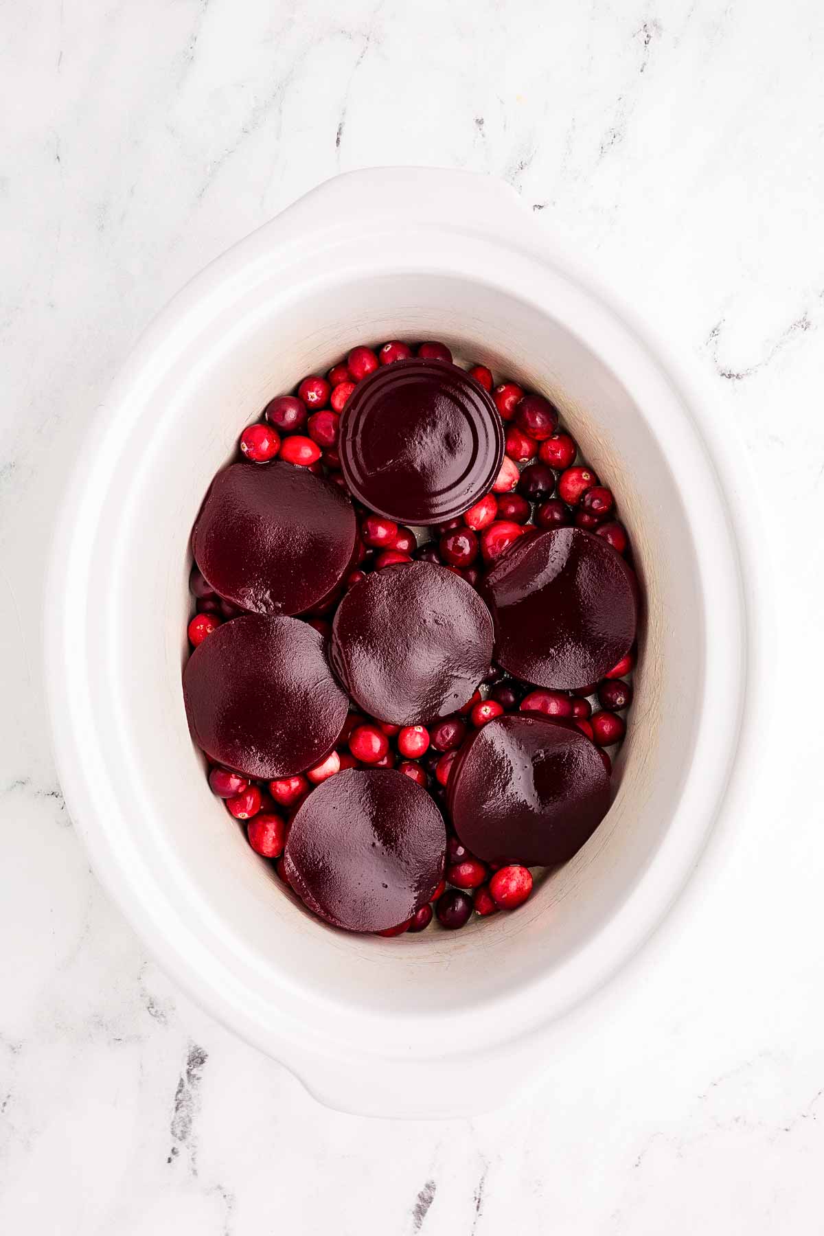 overhead view of cranberries and sliced cranberry sauce in white crock