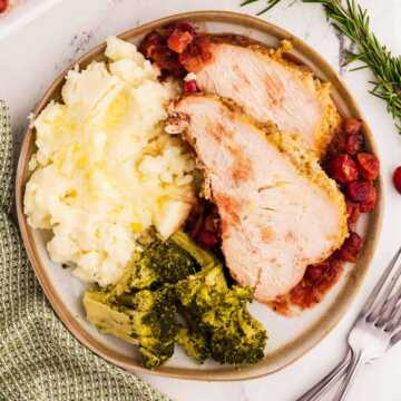 overhead view of sliced turkey breast on plate with mashed potatoes and broccoli