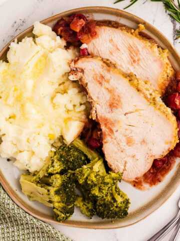 overhead view of sliced turkey breast on plate with mashed potatoes and broccoli