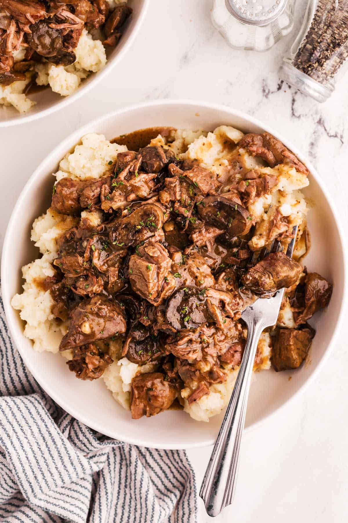 overhead view of beef tips in gravy on plate with mashed potatoes