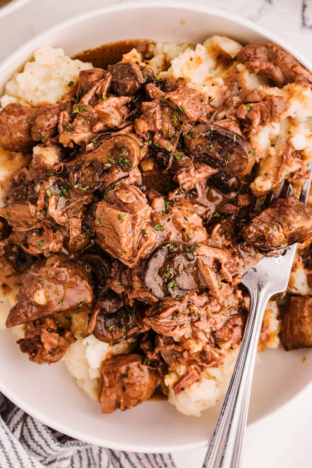 overhead view of beef tips and gravy on plate with mashed potatoes