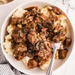 overhead view of beef tips in gravy on plate with mashed potatoes