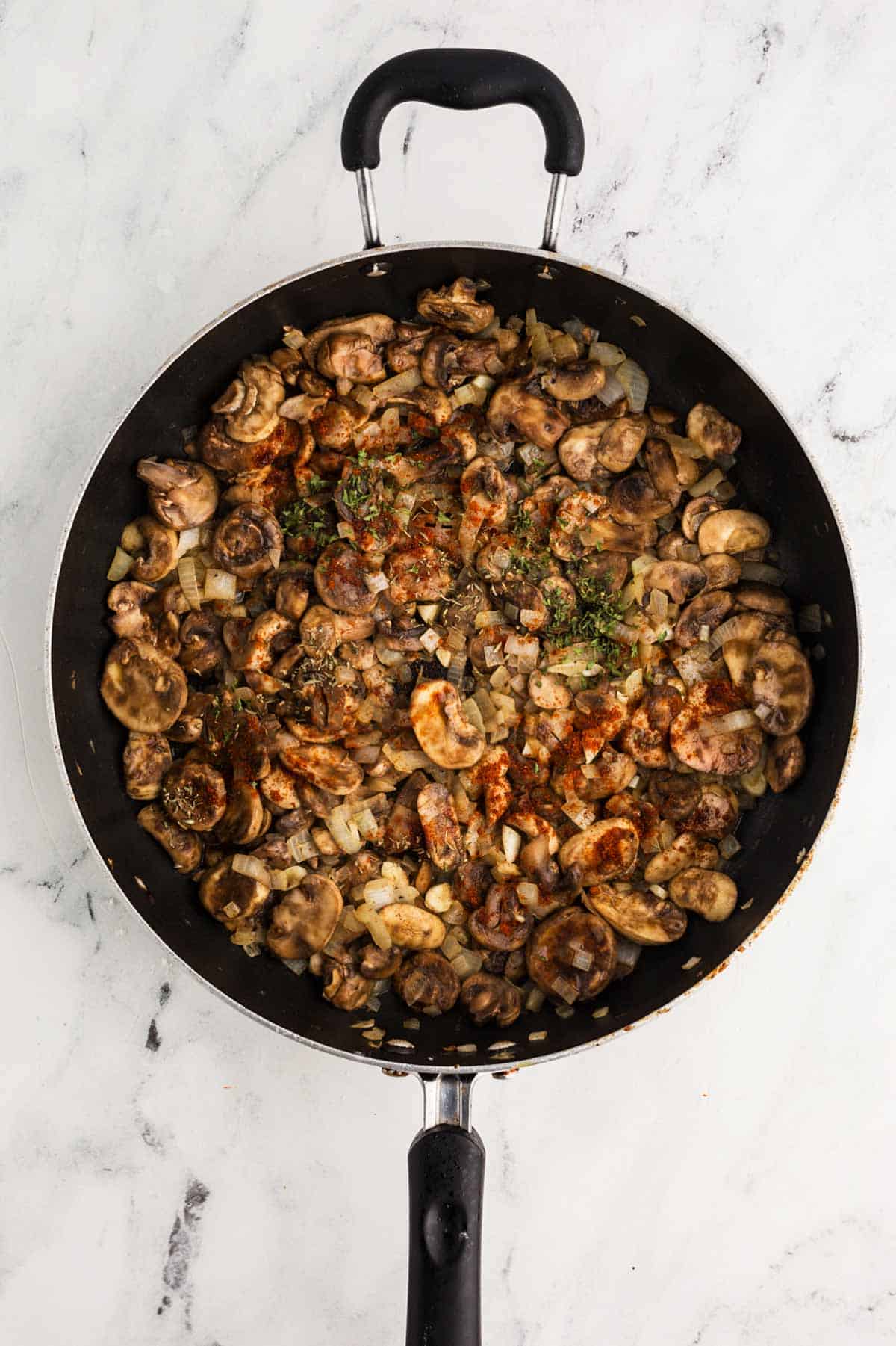 overhead view of cooked mushrooms and onion in skillet