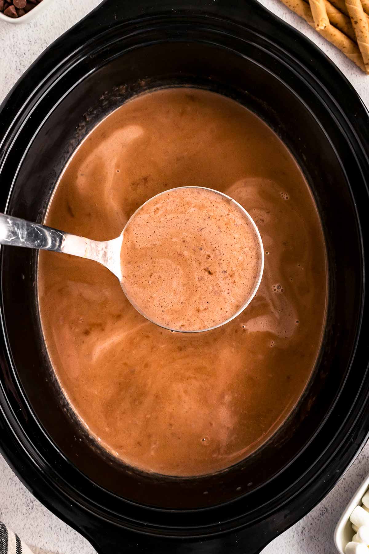 overhead view of hot chocolate with ladle in black slow cooker crock