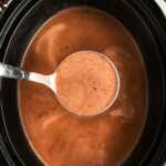 overhead view of hot chocolate with ladle in black slow cooker crock