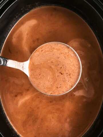 overhead view of hot chocolate with ladle in black slow cooker crock