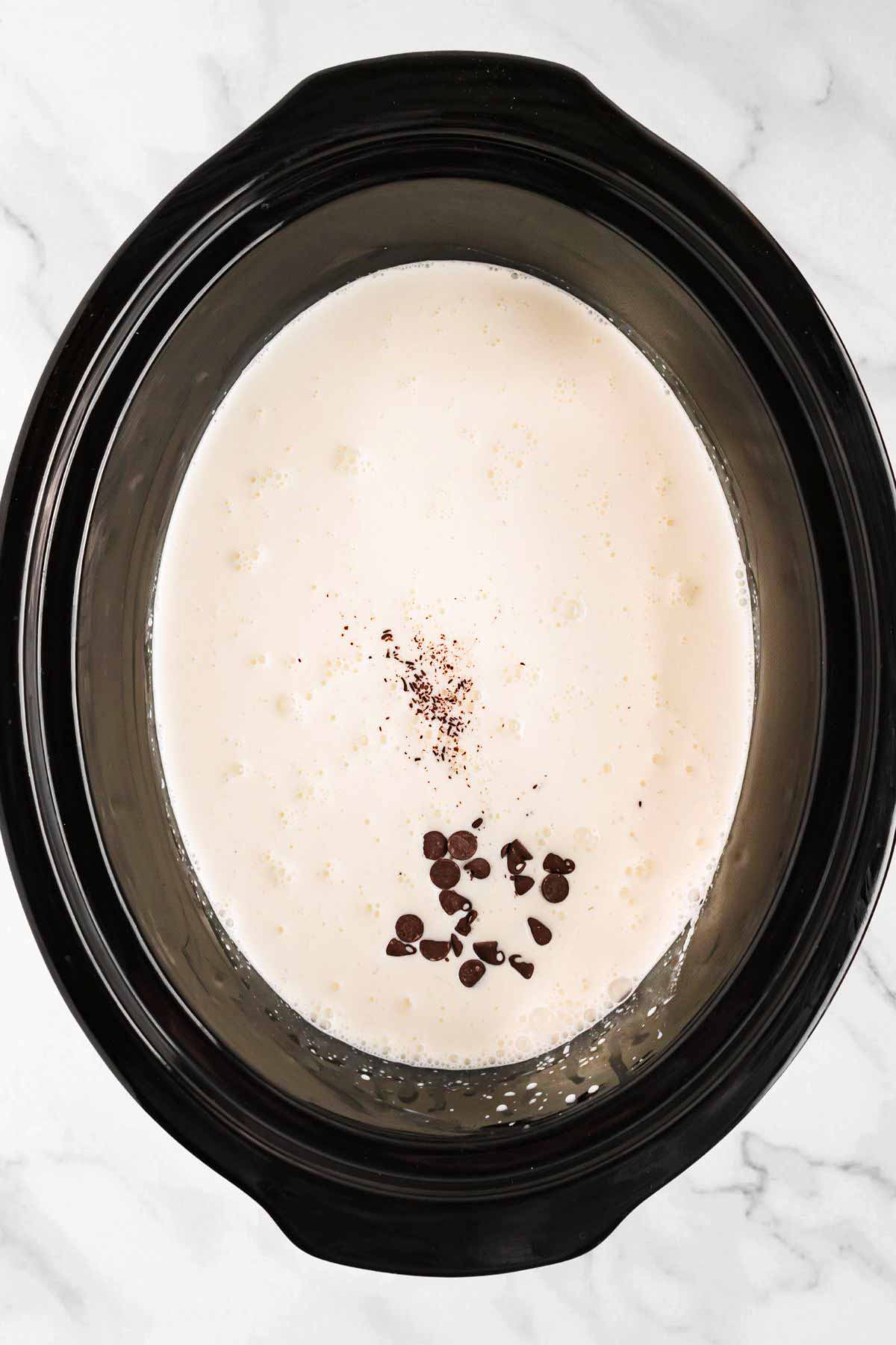 overhead view of cream and chocolate chips in slow cooker